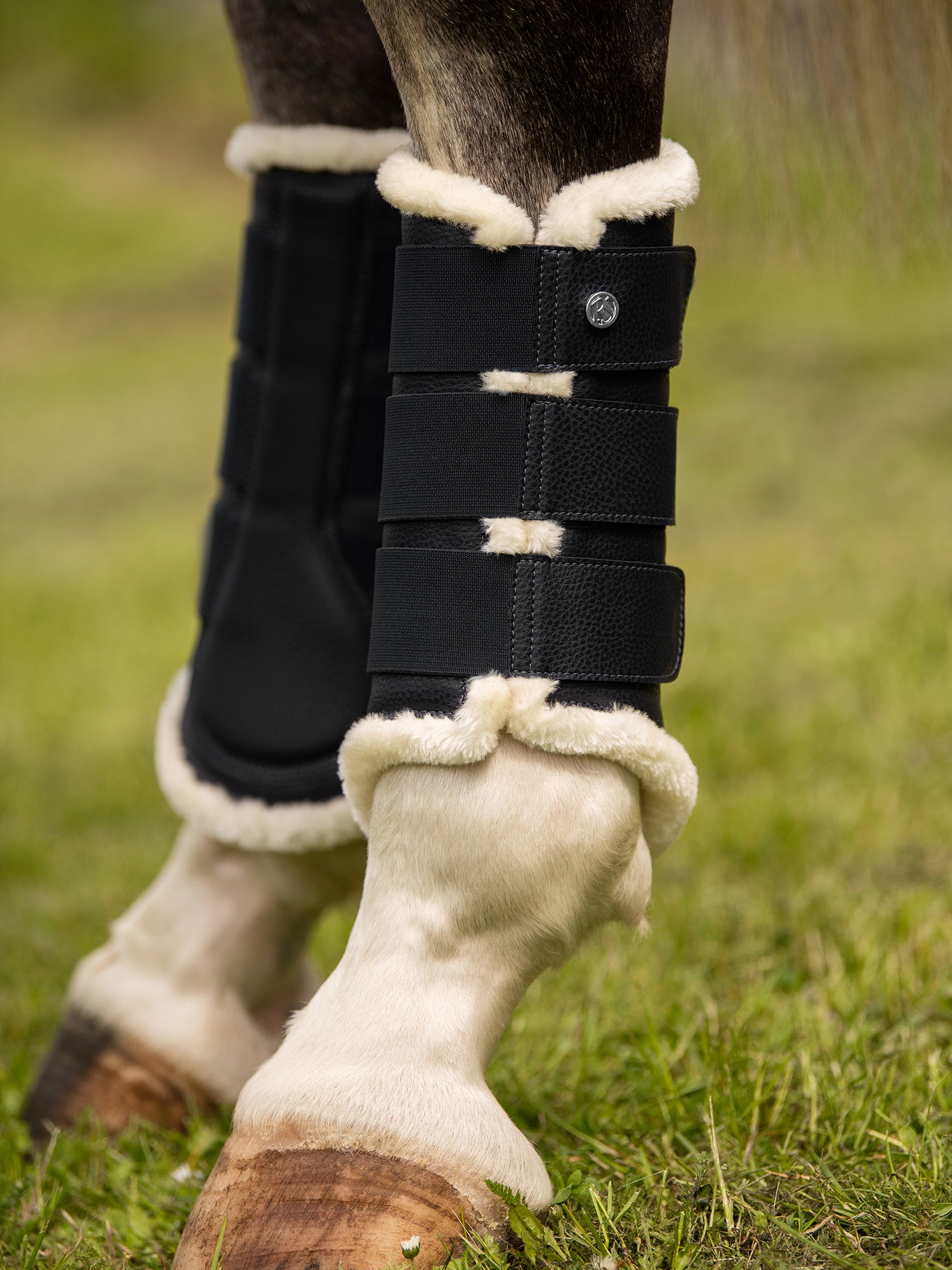 Brushing boots with elastic velcro fastening straps. The boots have a vegan leather surface and a padded patch on the inside for protection, and are fully lined with white faux fur. Front legs have two fastening straps and hind legs have three – all with one PS logo stud. 4-pack.