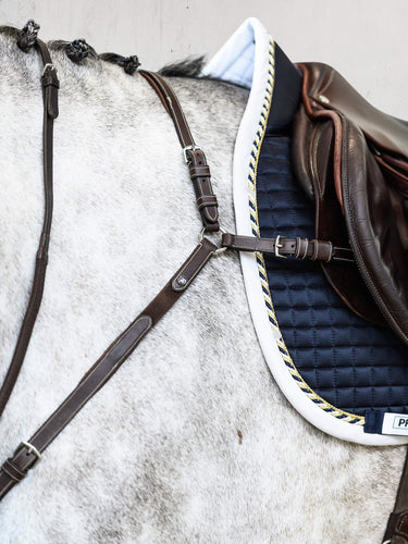 A well-worked breastplate, extra padded along the withers for additional comfort. The martingale is adjustable on both sides of the neck. The clever Snap It hooks make it unnecessary to open the reins to connect the equipment which is great both out of a practical and safety point of view.